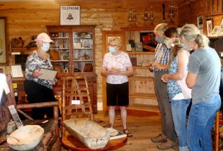Carolyn McCulloch and Joyce Flieler of the Pioneer Museum, showing Johhny Bay furniture to Emily, Laura, and Phil Schwager last Friday (July 24)